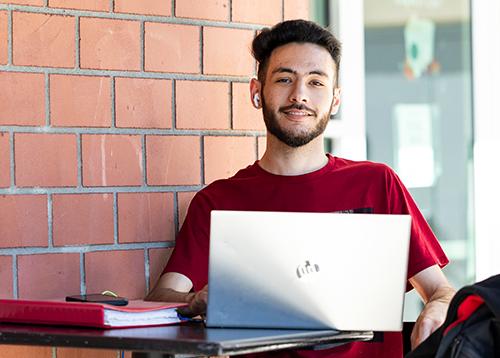 A young gentleman sitting on a table outside with his laptop