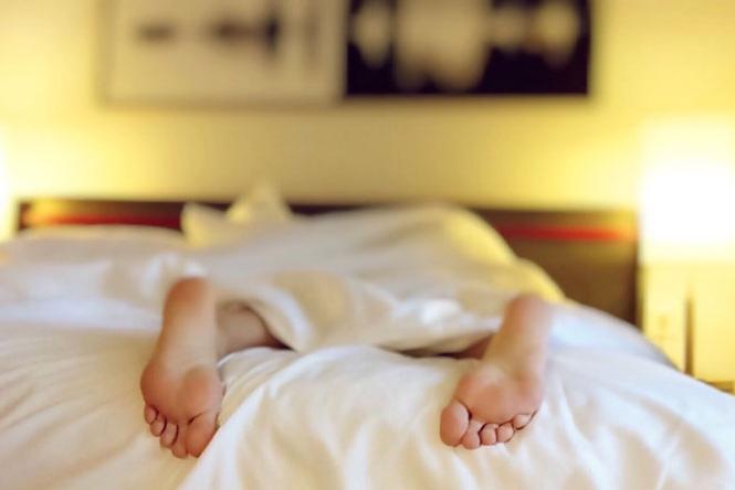 a person in bed with their feet sticking out from under the blanket